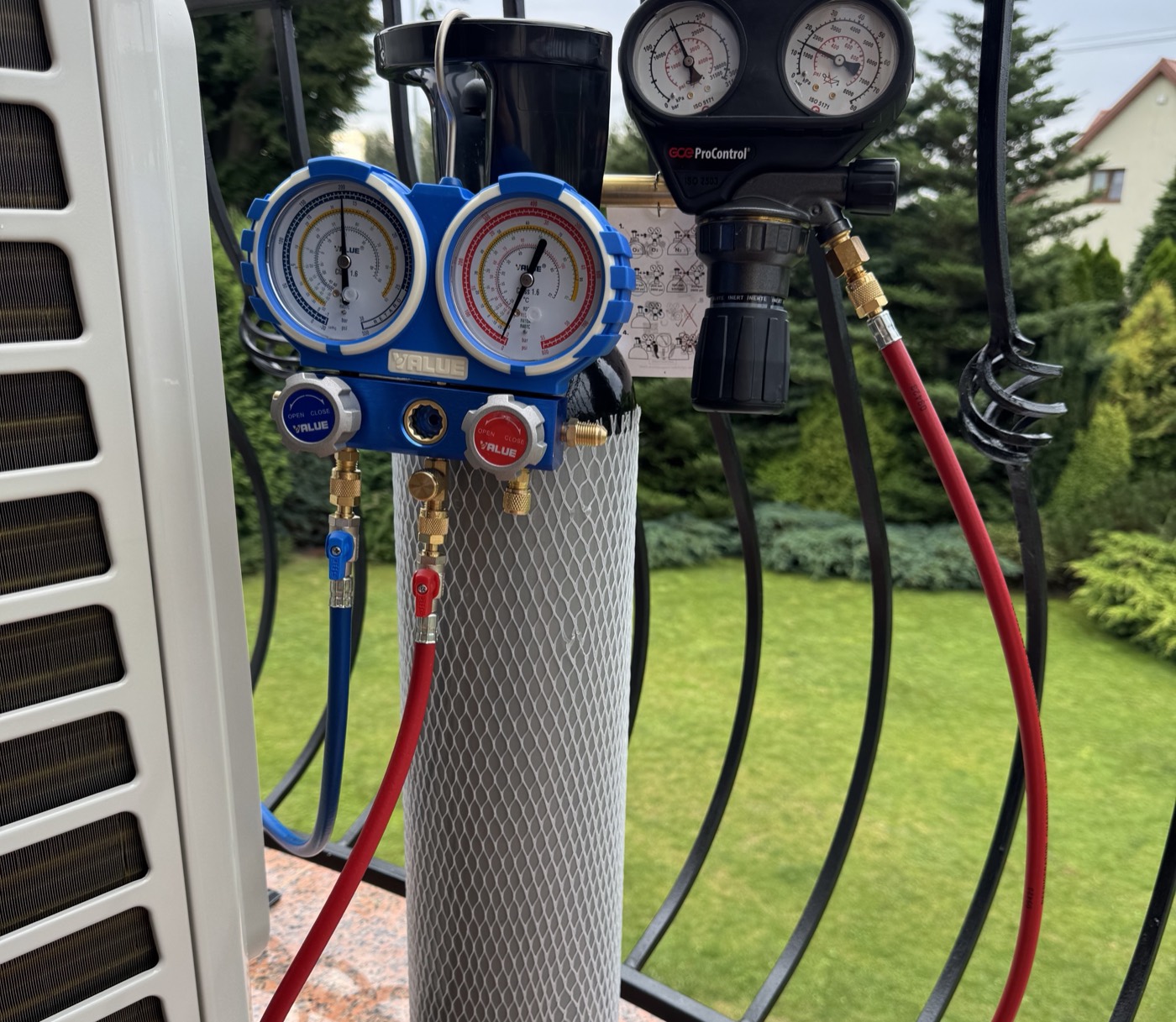 Butla i dwa zestawy manometrów podłączone do instalacji klimatyzacji na balkonie
