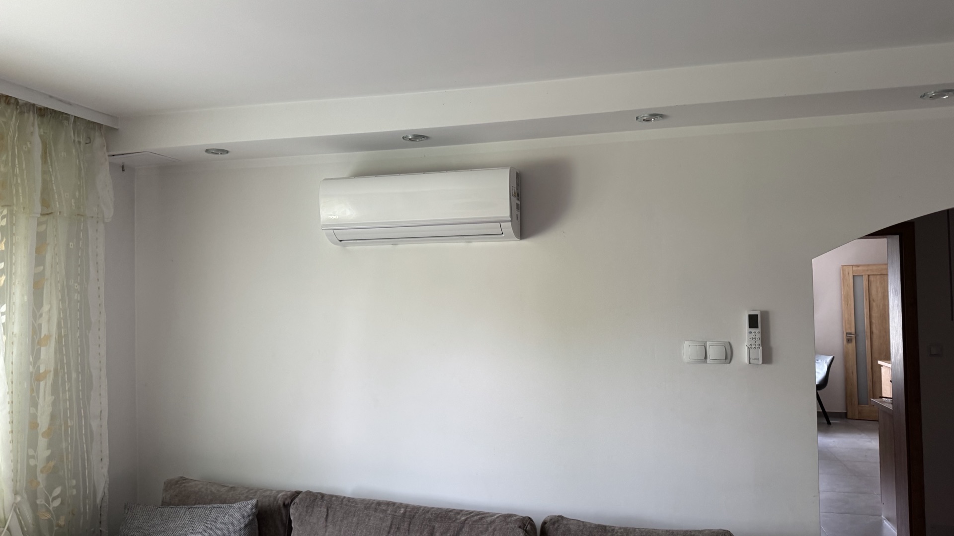 Salon z klimatyzatorem naściennym nad kanapą