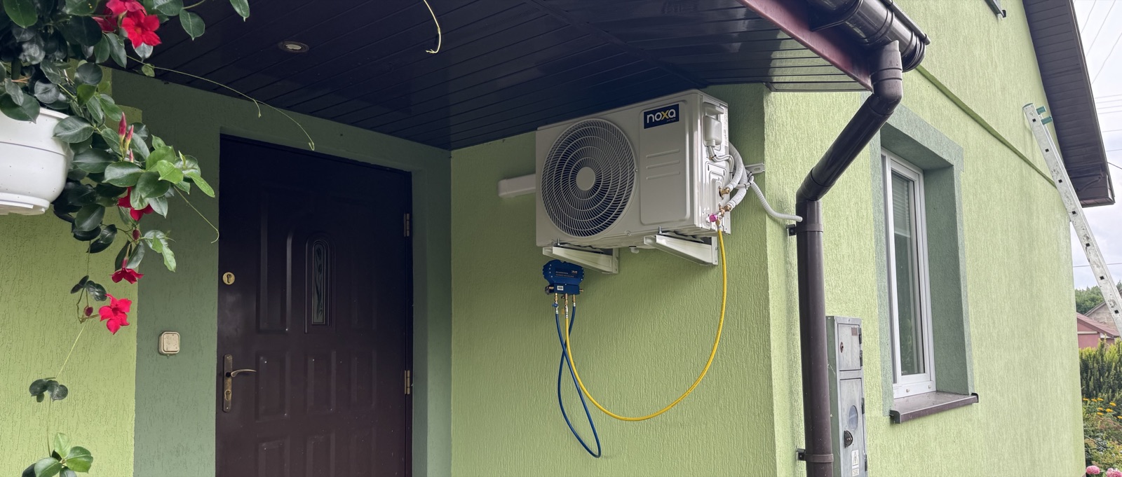Jednostka zewnętrzna klimatyzacji pod zadaszeniem wejścia do domu jednorodzinnego